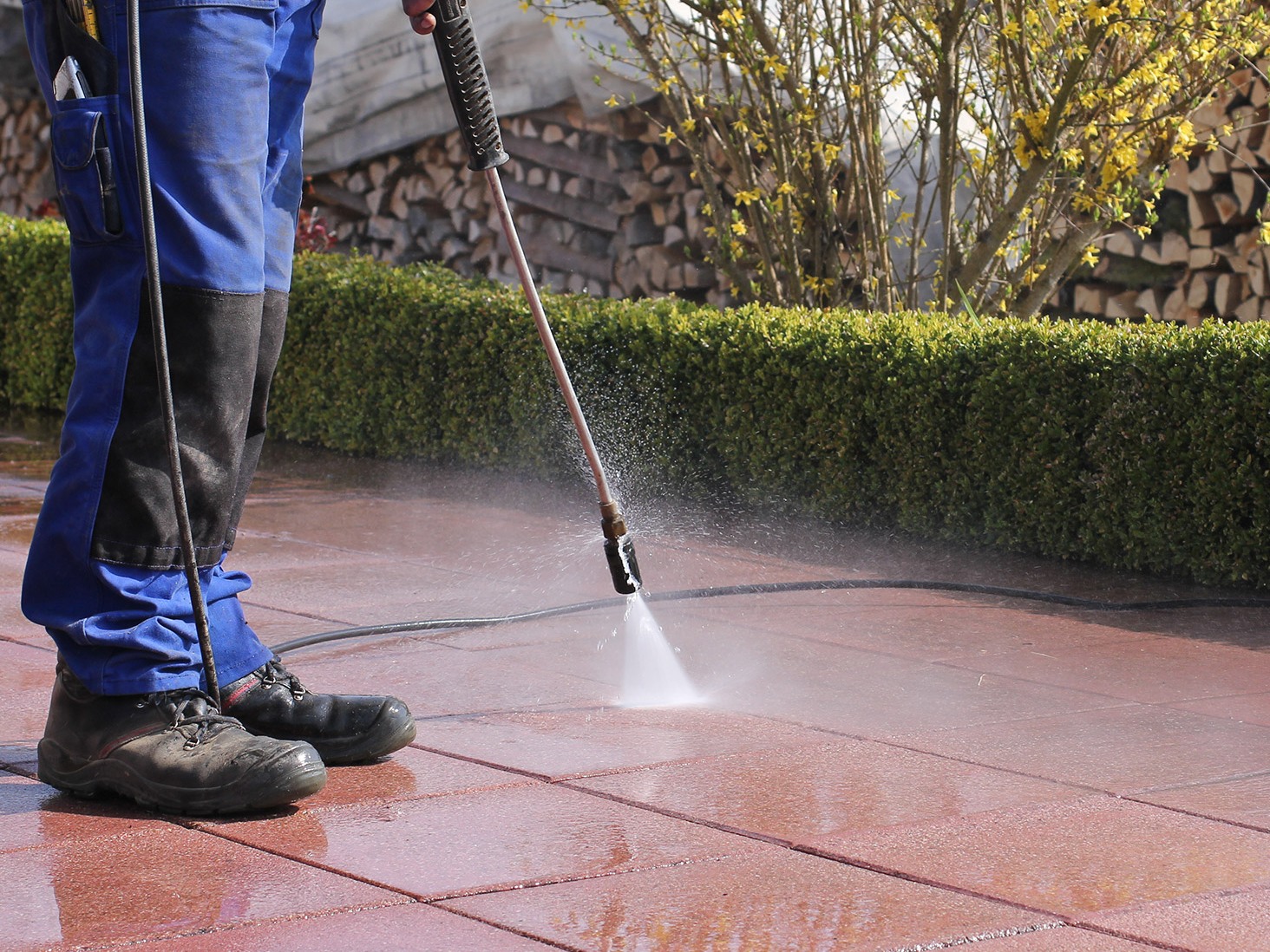 A man pressure washing tile outside